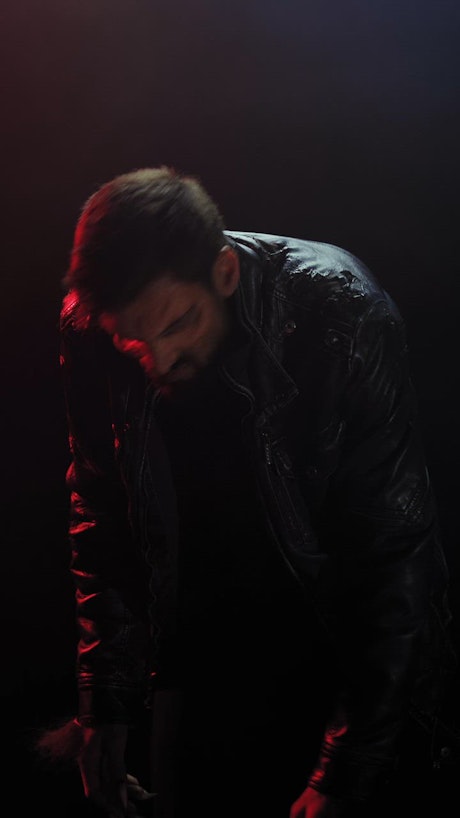 A werewolf wearing a leather jacket sniffs the air and looks to the camera.