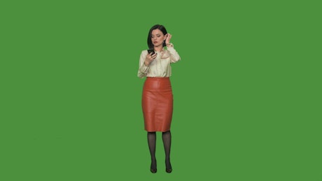 A woman answering a phone call on a green screen