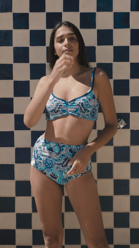 A woman in a bikini in front of a tiled wall