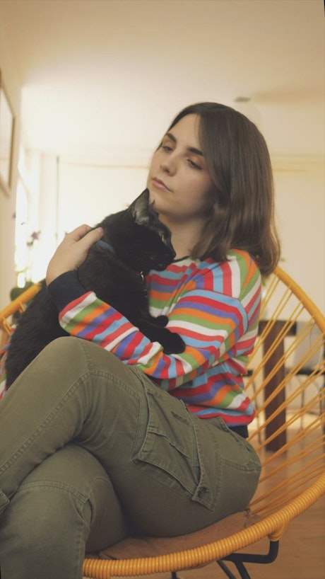 A woman petting a black cat.