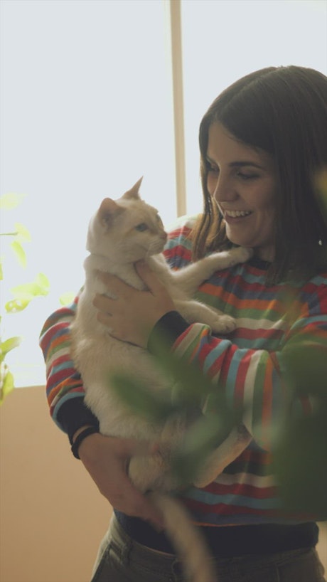 A woman petting and talking with her cat.