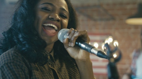 A woman singing with a microphone.