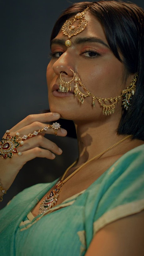 A woman using jewelry on her  hand and face posing.