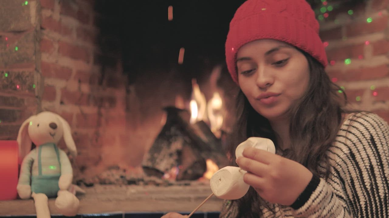 A woman warms marshmallows LIVEDRAW  in the fire of her fireplace