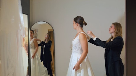 A young beautiful bride trying a wedding gown for the first time in front of the mirror.