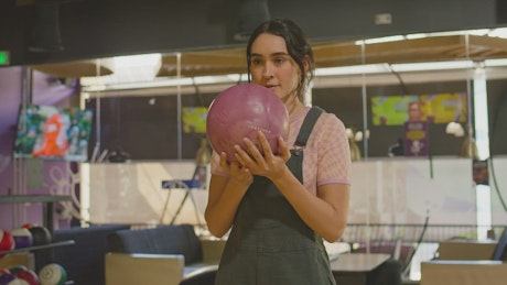 A young brunette woman celebrates a bowling shot.