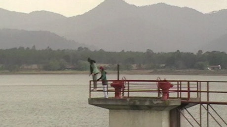 A young couple plays and enjoys the lake view from the pier.