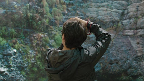 A young explorer with a professional photo camera takes a photo of a waterfall.