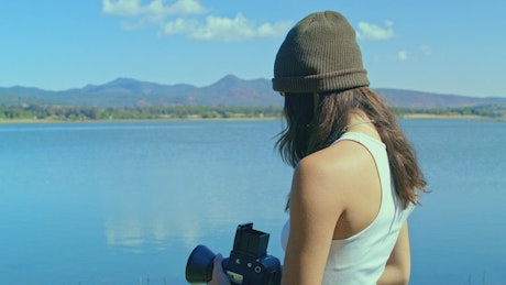 A young filmaker capturing a stunning landscape with an old camera.