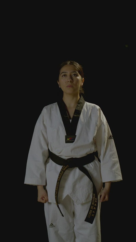 A young karateka woman makes a reverence movement.