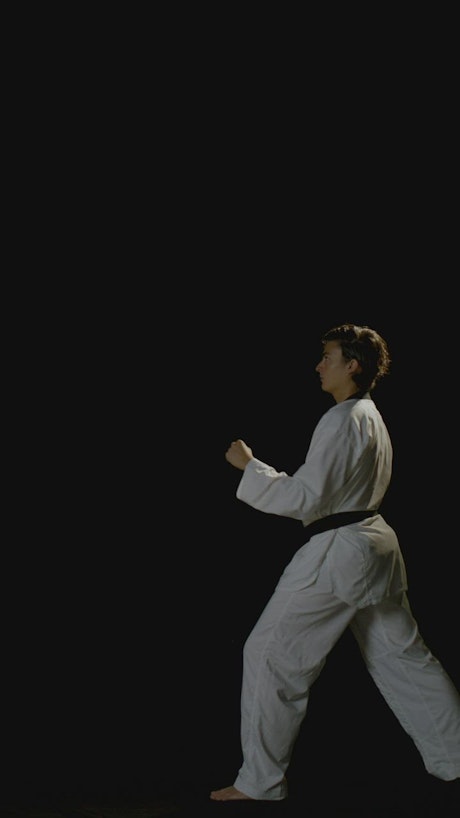 A young karateka woman performs a karate kick.