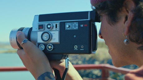 A young man adjust the lens of an old film camera.