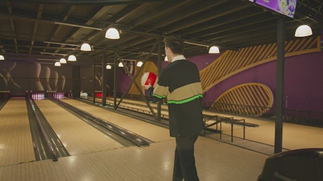 A young man makes a shot at the bowling center.