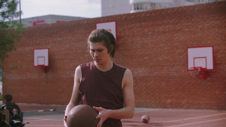 A young man on the basketball court bouncing the ball