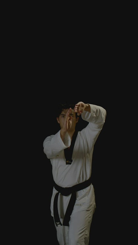 A young man practice karate wearing a white kimono.