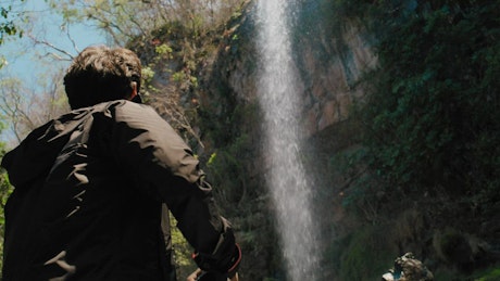 A young man prepares the camera to take a picture of the waterfall.