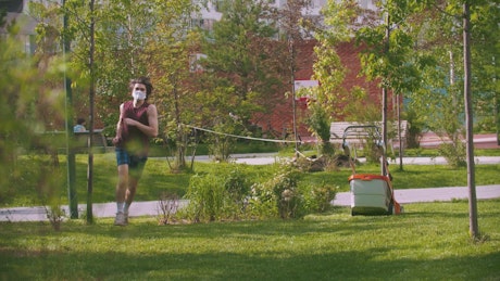 A young man with a medical mask exercising in the park.