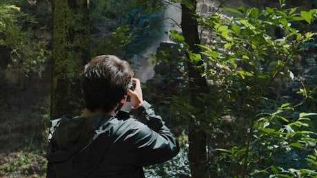 A young photograper taking pictures in the jungle.