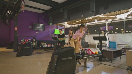 A Young teenager makes a shot at the bowling place.