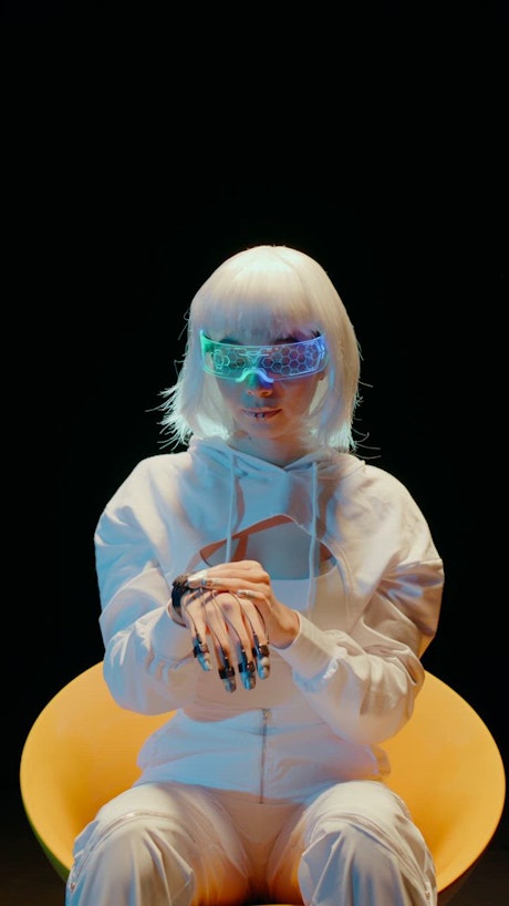 A young woman in white attire turn on her hand sci fi device and starts moving her hand like navigating in the digital realm.