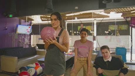 A young woman makes a shot at the bowling center.