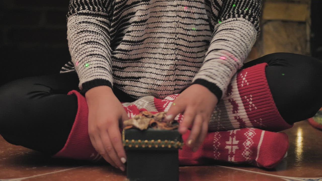 A young woman opens a Christmas  LIVE DRAW present