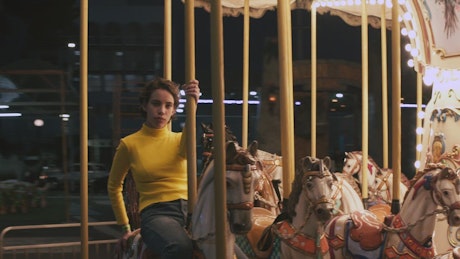 A young woman riding a horse at a carrousel