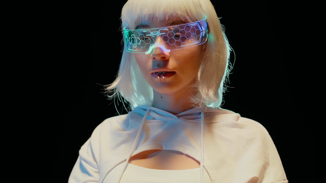 A young woman wearing futuristic VR glasses focuses on an unseen task making subtle movements with her hads.