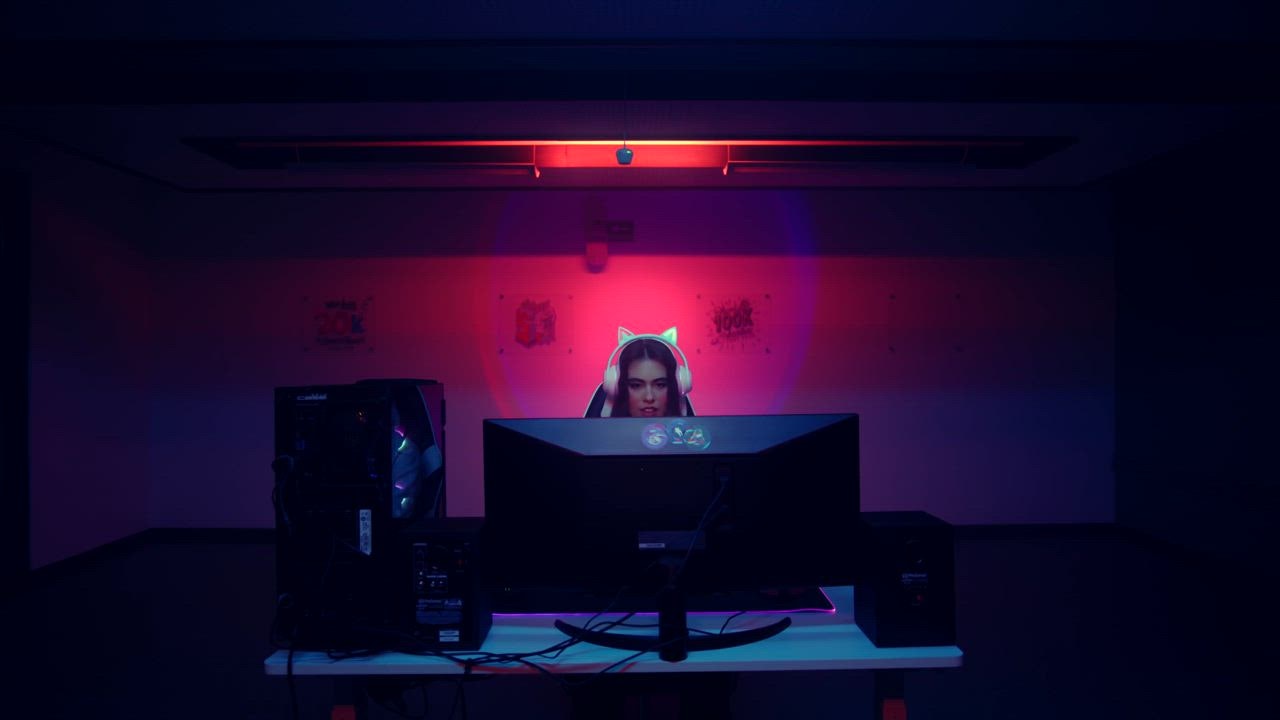 A young woman with kitty headphones enjoys a gaming session on pc gaming set up.