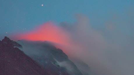 Active volcano smoking during the starry night.