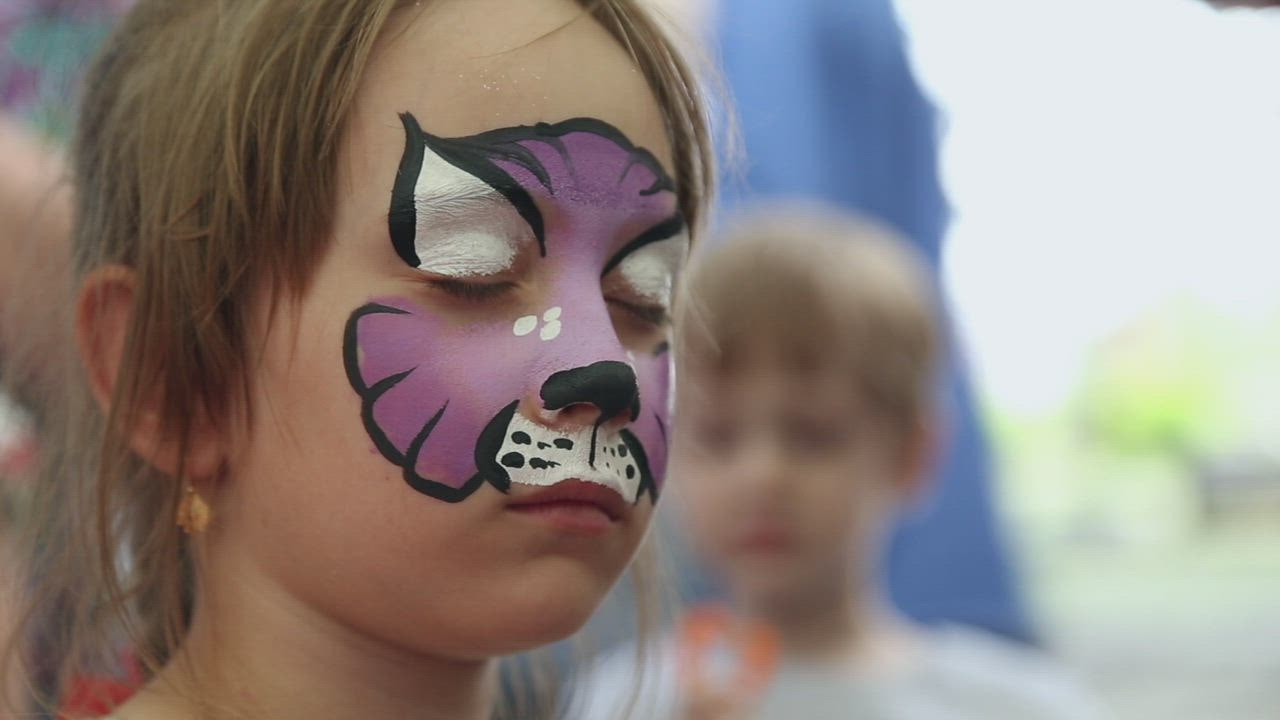 Adding Glitter To Face Paint Of A Purple Cat On A Child - Free Stock Video