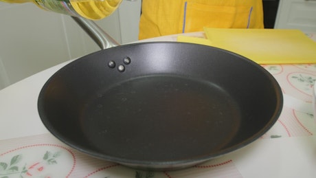 Adding oil to a frying pan.