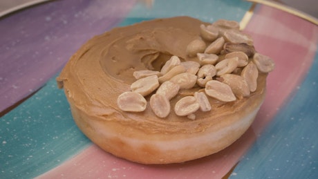 Adding peanuts to a peanut butter donut.