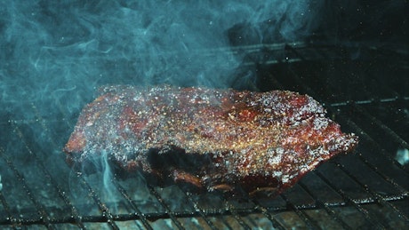 Adding spices to barbecue meat in the grill.