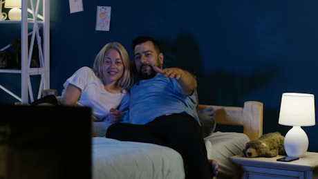 Adult couple watching TV in the bedroom