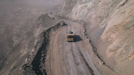 Aerial footage of a truck driving along a road above a large quarry.
