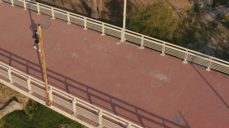Aerial shot of a girl jogging on a footbridge