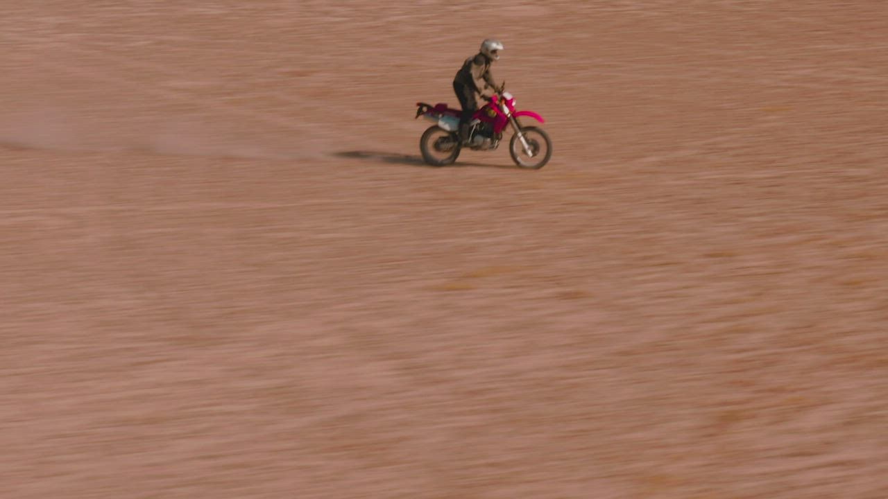 Pelacakan udara seorang pria LIVE DRAW dengan sepeda motor di padang pasir