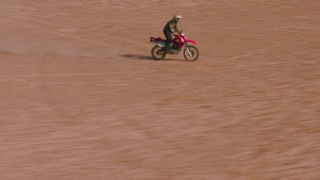 Aerial tracking of a man on a motorcycle in the desert.