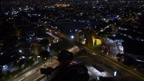 Aerial view of a big yellow monument with traffic around at night.