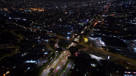 Aerial view of a big yellow roundabout with traffic at night.