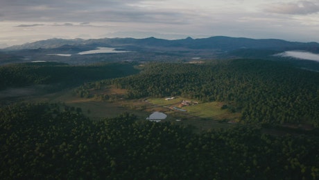 Aerial view of a green forest with mountains and lakes.