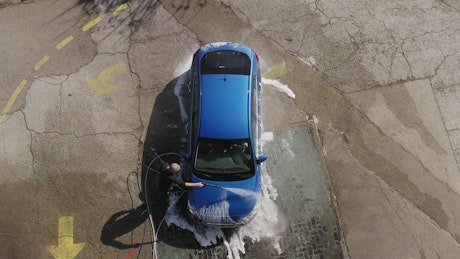 Aerial view of a man washing his blue car.