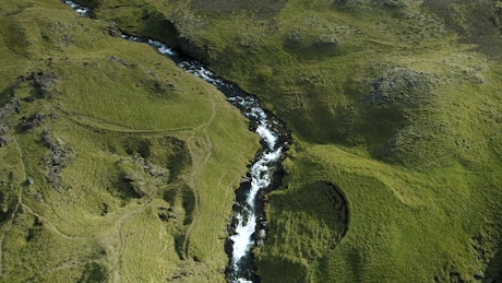 Aerial view of a river and a waterfall on a green land