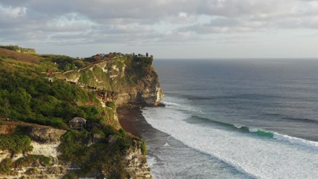 Aerial view of high cliffs on Indonesian coast and ocean waves.
