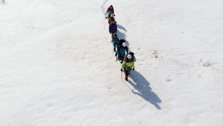 Aerial view of hikers walking through the snow high in the mountains.