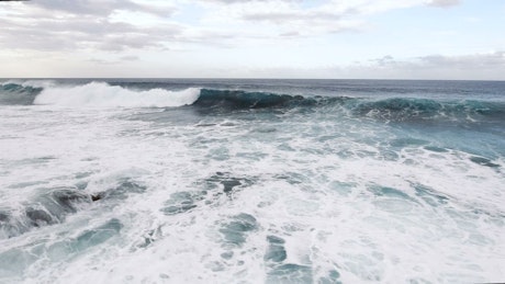 Aerial view of huge ocean waves crashing on shore.