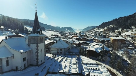 Aerial view of snow covered mountain village and church.