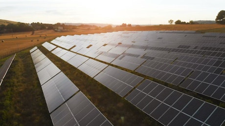 Aerial view of solar panels in a field at sunset.