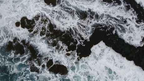 Aerial view of the ocean crashing on the shore.